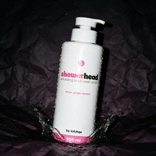 Shower Head exfoliating body wash gel with splash on deep plum backdrop