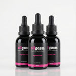 Three black bottles labeled 'oilgasm' on a light gray background